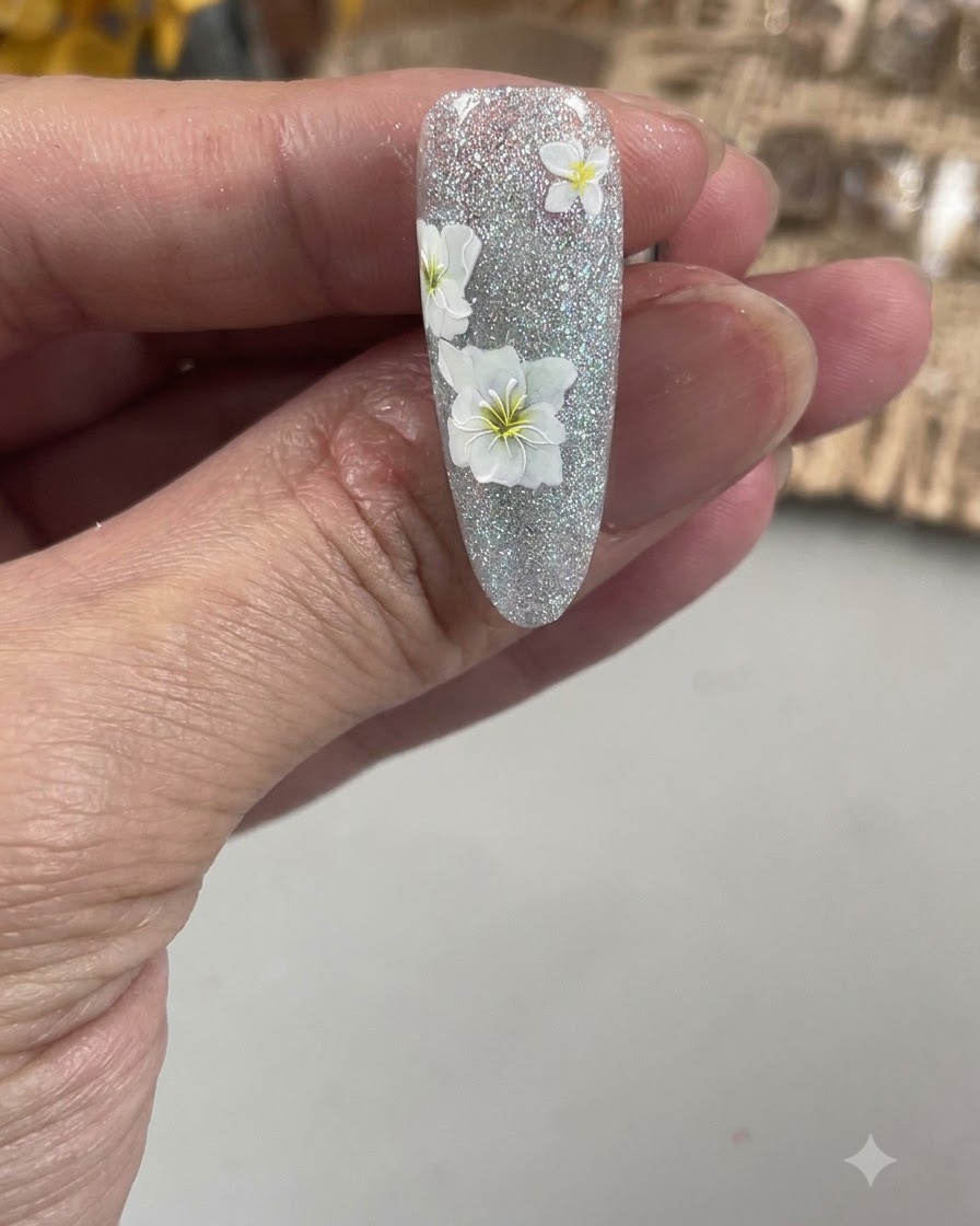 Eine Nahaufnahme eines feinen Nail-Art-Pinsels, der die zarten Blütenblätter einer weißen Blume auf einem strukturierten Nagel umrandet.