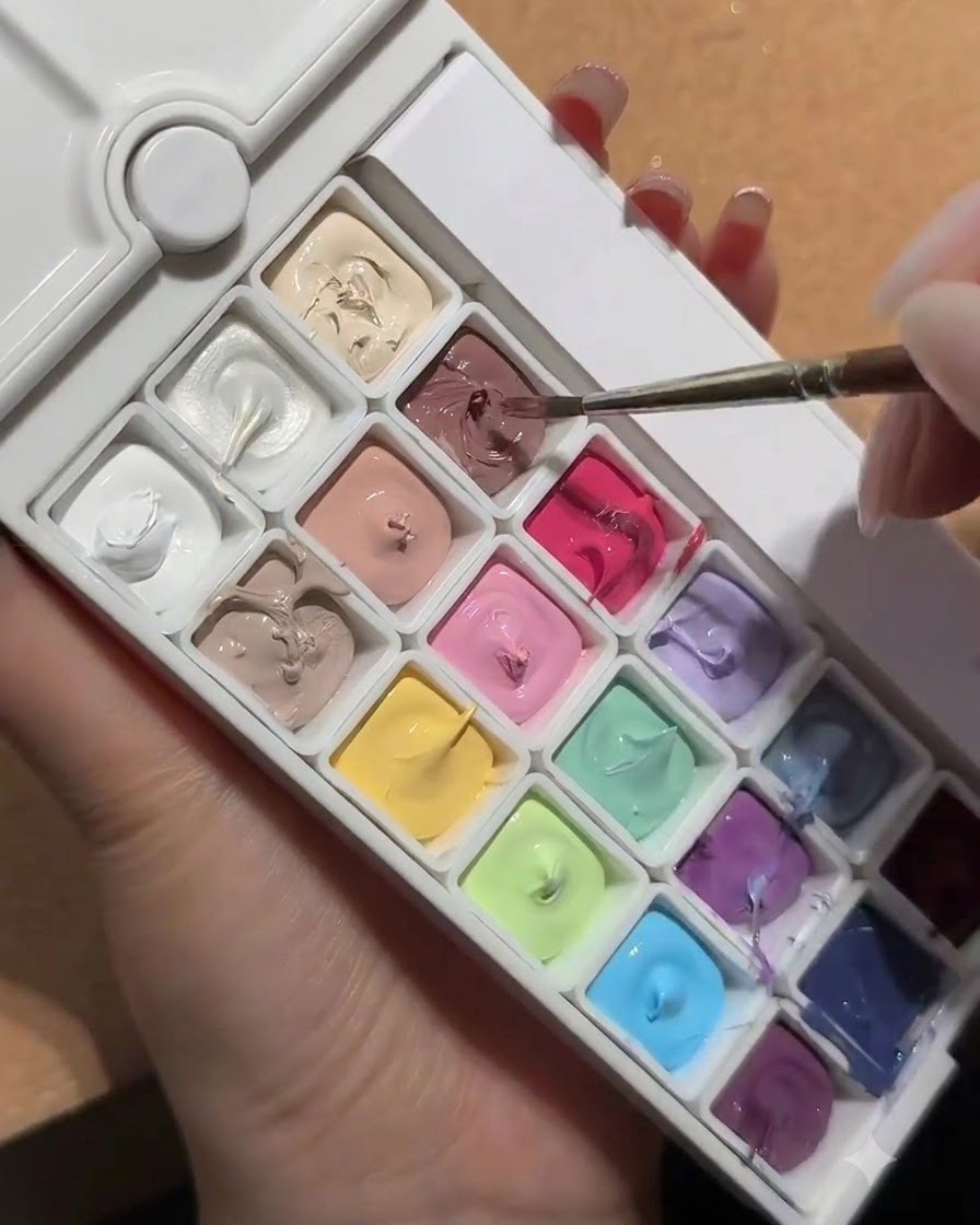 Ein Nagelpinsel taucht in eine Palette mit einer quadratischen Mulde aus White Peach Nude Gel.