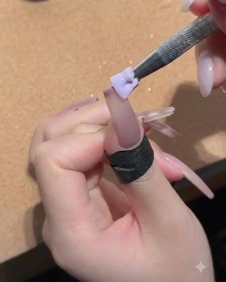 Ein kleiner Schwamm, gehalten von einem Metallwerkzeug, tupft Pfirsich-Nude-Gel auf die Nageloberfläche.