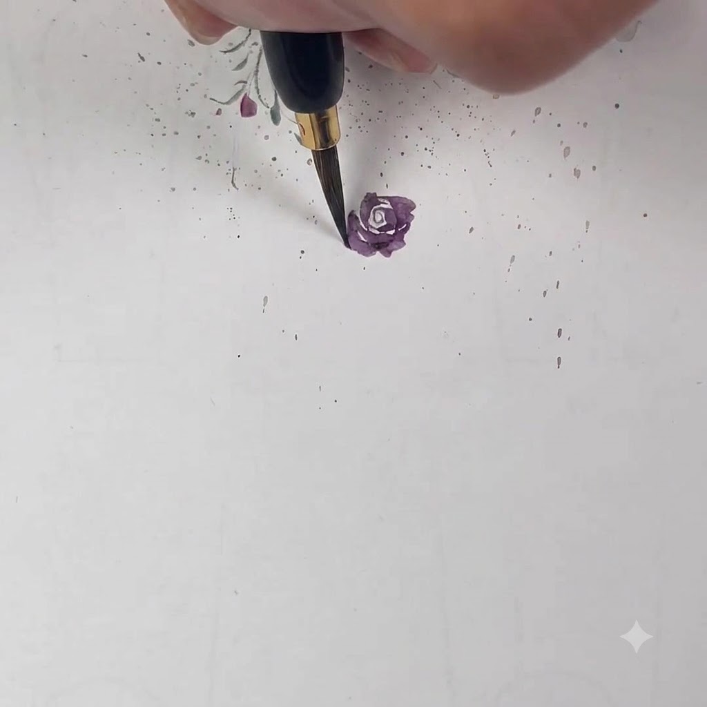 Ein feiner Pinsel fügt ein helleres lila Blütenblatt hinzu, das die vorige Schicht zur Hälfte überlappt.