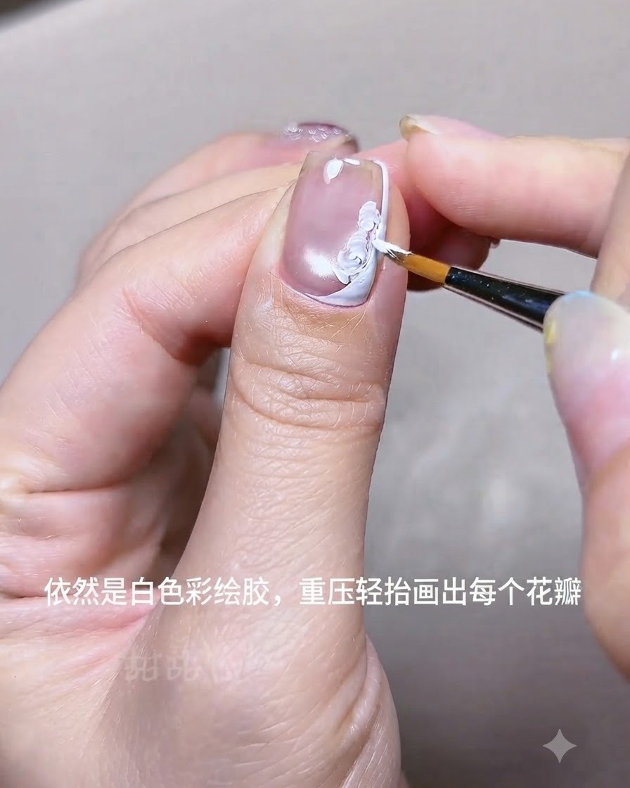 Eine Nahaufnahme einer Hand, die mit einem feinen Liner-Pinsel weiße Acrylgel-Blumenblüten auf einen Nagel in der Nähe einer weißen French-Spitzenlinie malt.