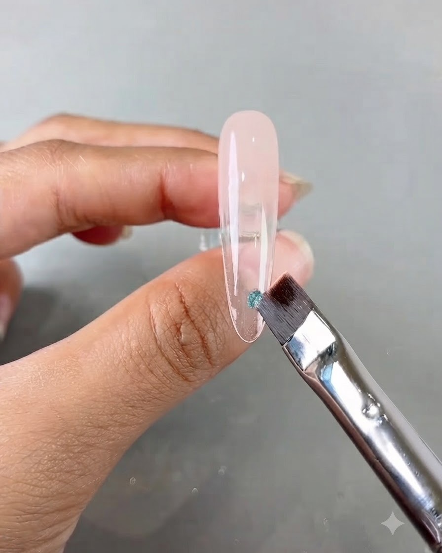 Ein Nagelpinsel, der ein kleines Stück blaue Paillette auf einen langen, klaren Übungsnagel aufträgt.