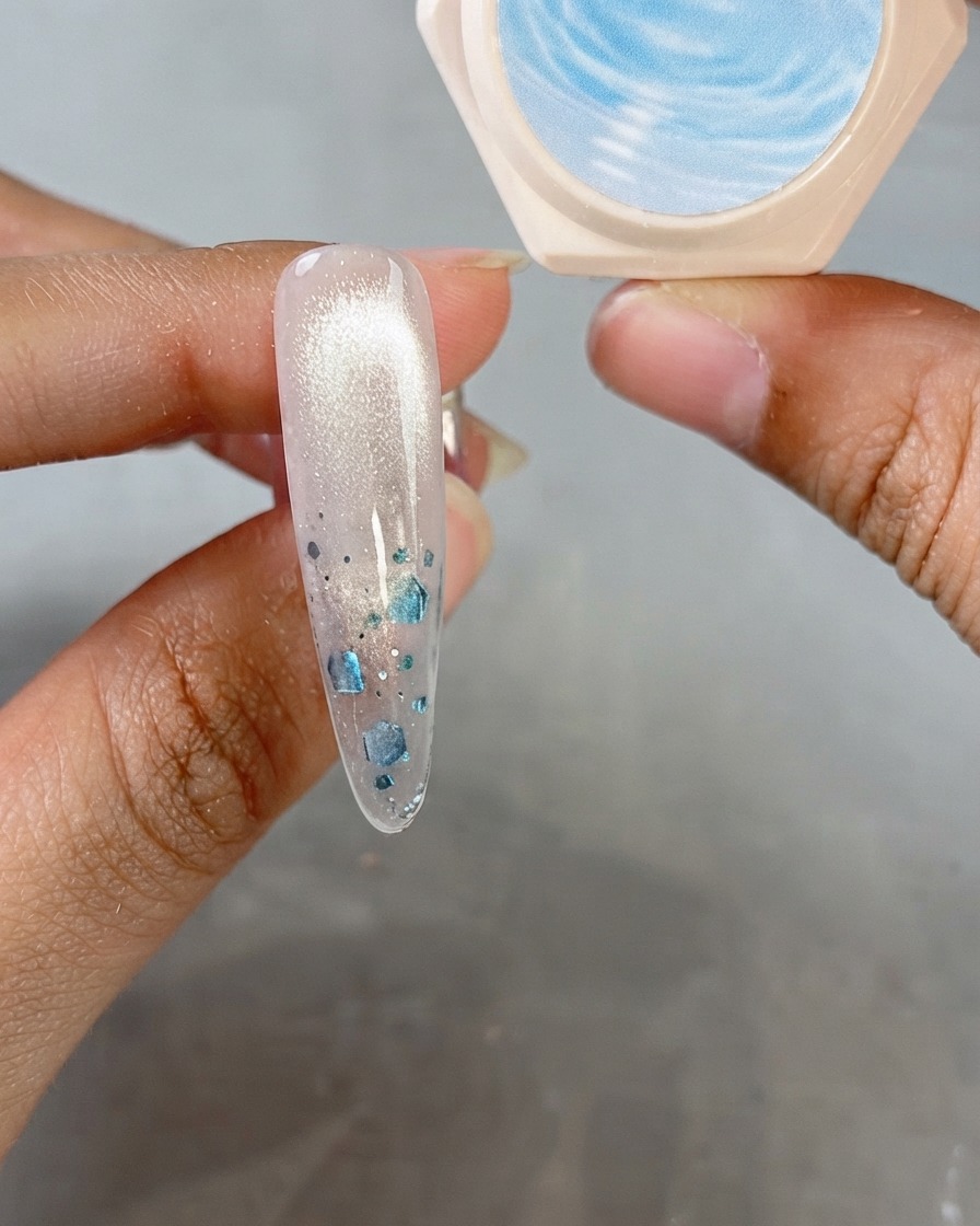 Ein Mandelnal zeigt ein schimmerndes Cat-Eye-Finish mit einem Glas Kristallgel im Hintergrund.