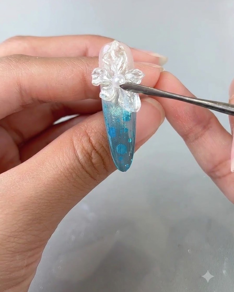 Eine Nahaufnahme eines manikürten Fingers, der eine finale klare Überlack-Anwendung über einem strukturierten Blumen-Nail-Art-Design erhält.