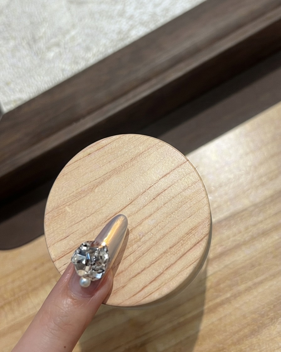 Nahaufnahme eines Zeigefingernagels, der mit einer geschwungenen Reihe winziger funkelnder Strasssteine dekoriert ist.