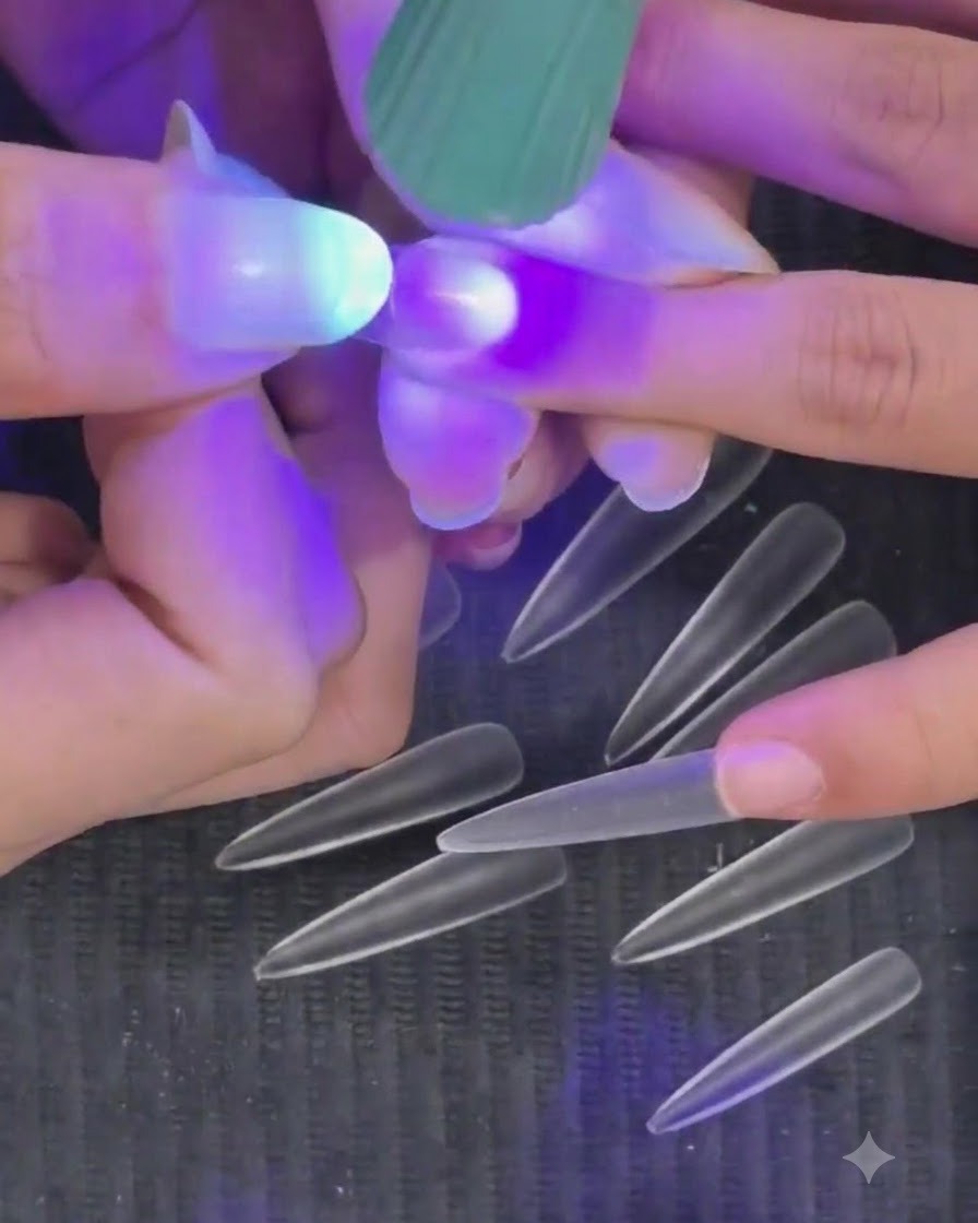 Eine Hand hält eine violette Mini-UV-LED-Taschenlampe über einen Fingernagel, um einen halbausgehärteten Nageltip zu härten.