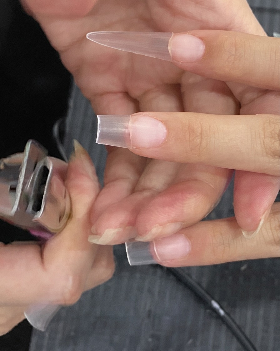 Nageltip-Schere beim Kürzen der überschüssigen Länge einer künstlichen Nagelverlängerung.