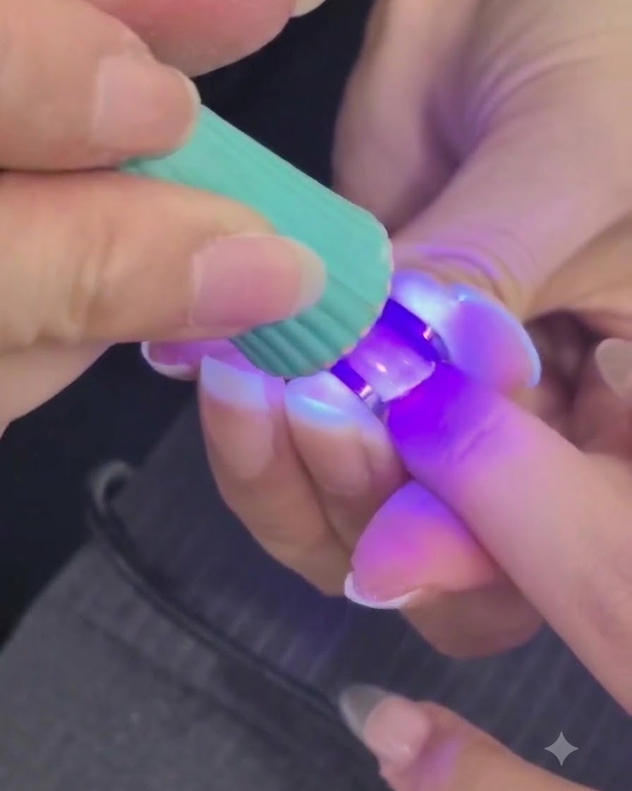 Eine Mini-UV- oder LED-Lampe härtet eine strukturierte Nagelgelschicht auf einem Finger aus.