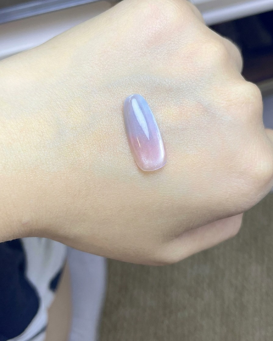 Eine Nagelspitze mit einem rosa Blush-Farbverlauf beim Aushärten unter einer UV/LED-Lampe.