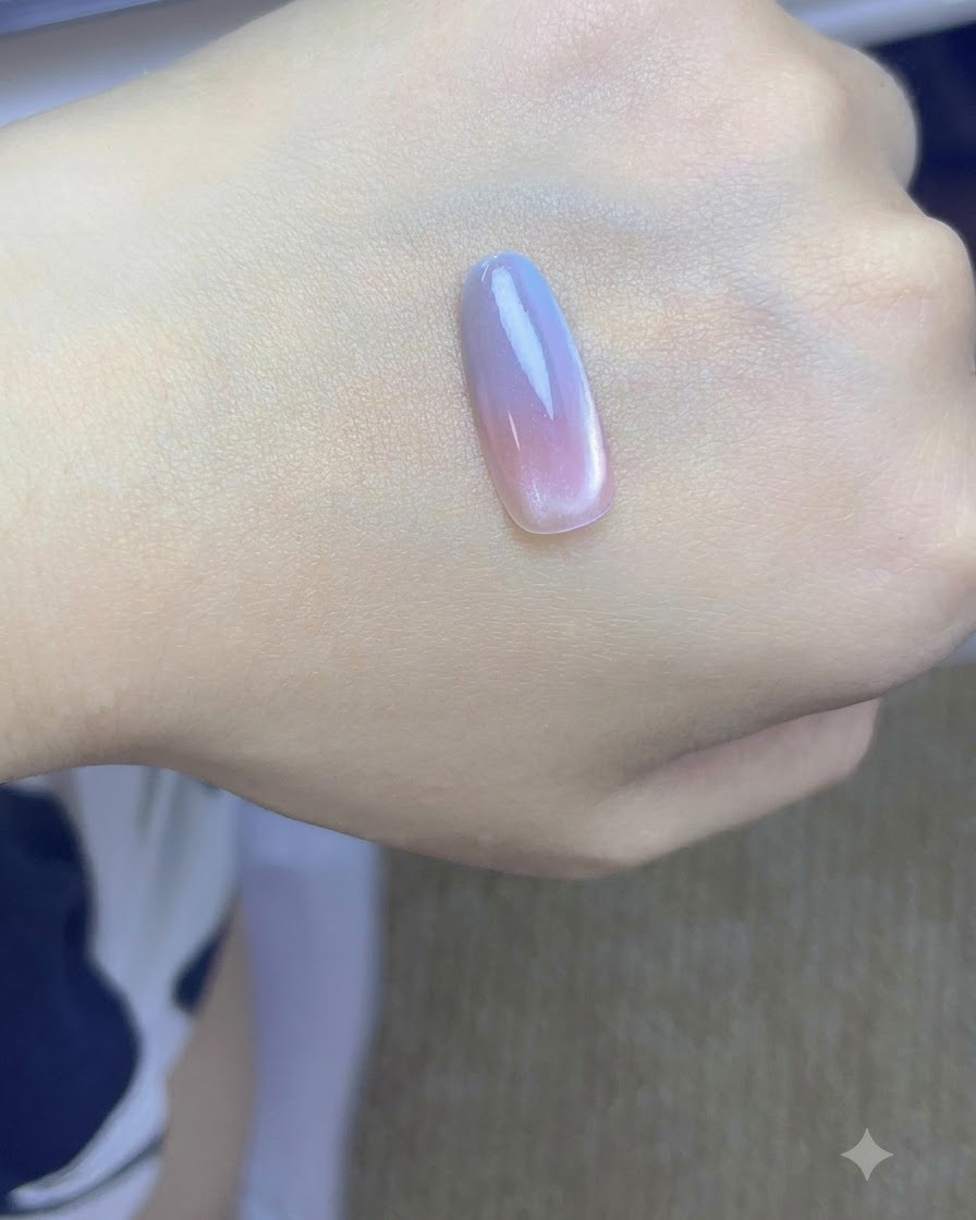 Eine Nagelspitze mit rosa und blauen Farbverlaufsschichten beim Aushärten unter einer UV/LED-Lampe.