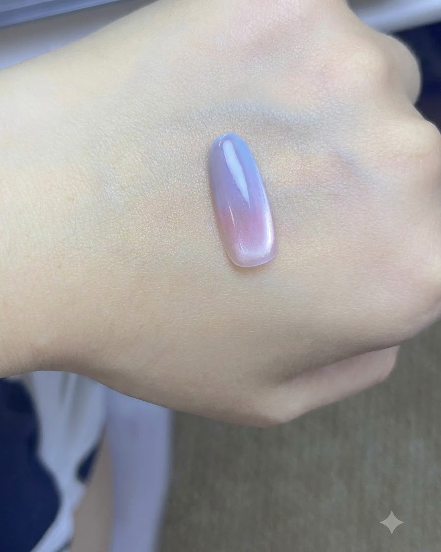 Ein Pinsel tupft eine zweite Schicht blauen Gels auf die Nagelspitze einer Hand.