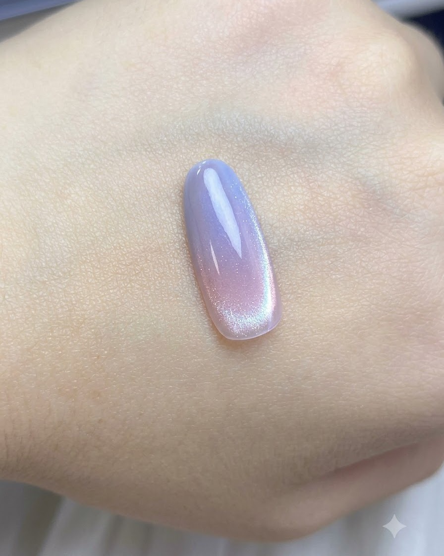 Ein Pinsel trägt eine Schicht transparenten Nude-Cat-Eye-Nagellacks über die Farbverlaufs-Nagelspitze auf.