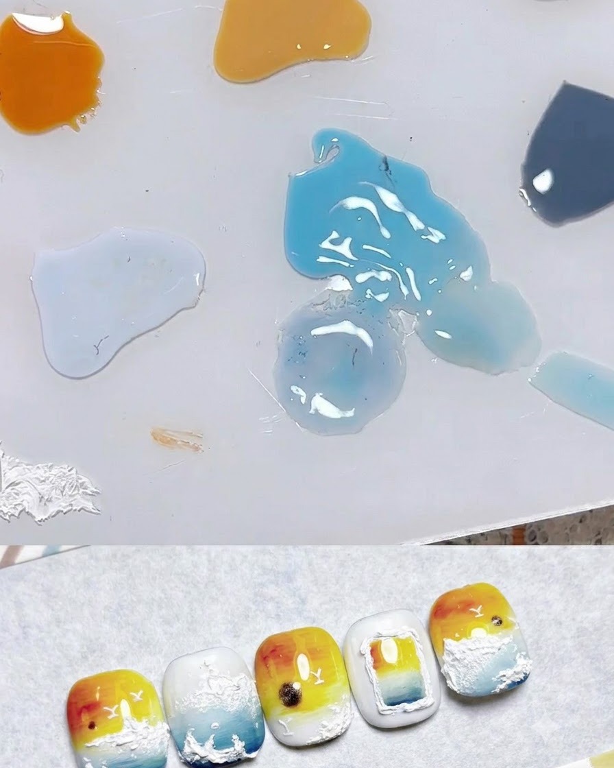 Eine Mischpalette mit Tropfen verschiedener Gel-Farben einschließlich blassem Gelb, Orange und Blau neben Nagelkunstproben.