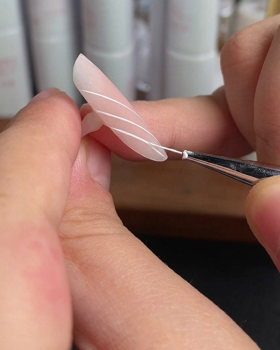 Ein Ringfinger-Nagel mit weißen parallelen Linien härtet unter Lampenlicht aus.