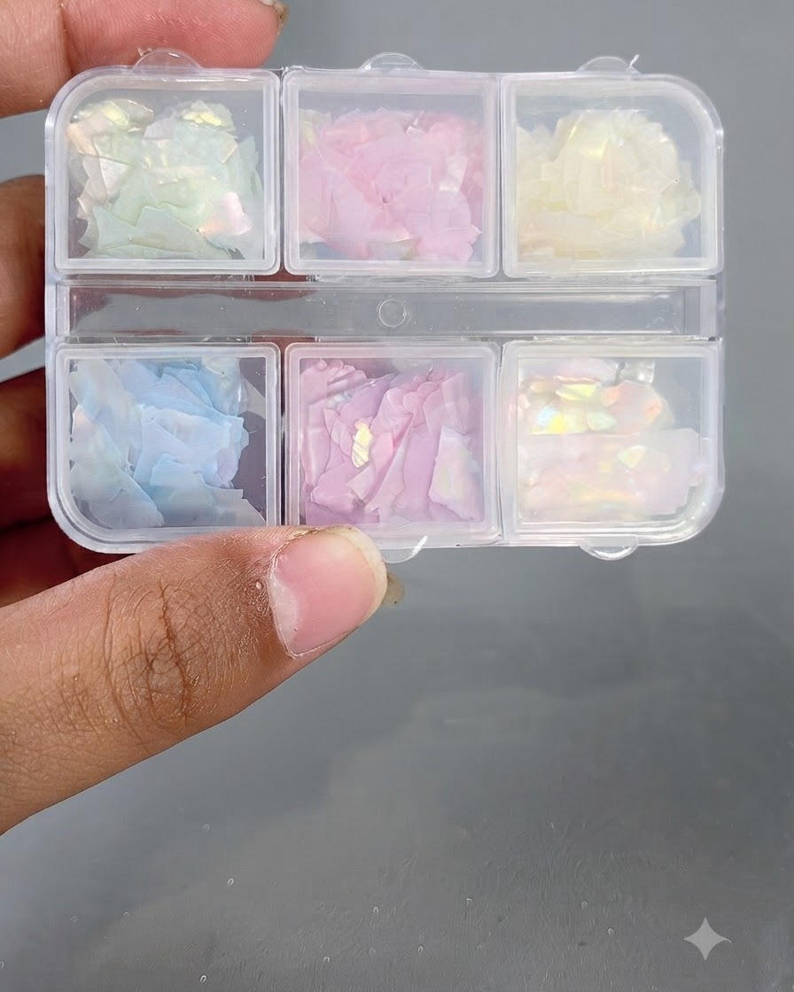 Eine mehrfächerige Aufbewahrungsbox gefüllt mit verschiedenen bunten, irisierenden Muschelstücken.