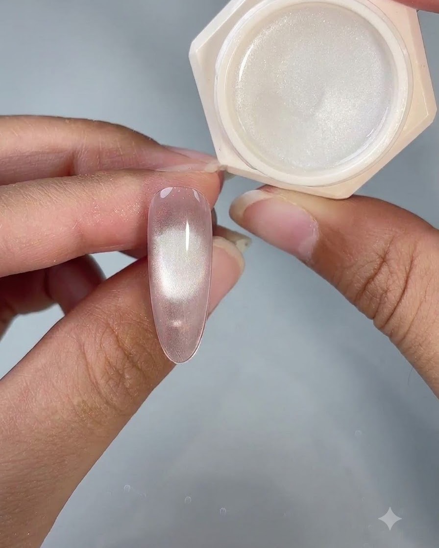 Ein fertiger Cat-Eye-Gel-Nagel neben seinem geöffneten Produktglas unter Studiobeleuchtung.