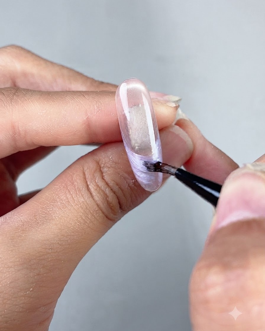 Ein feiner Kunst-Linienpinsel zieht eine Perlglanz-French-Tip-Linie auf einer klaren, modellierten Nagelverlängerung.