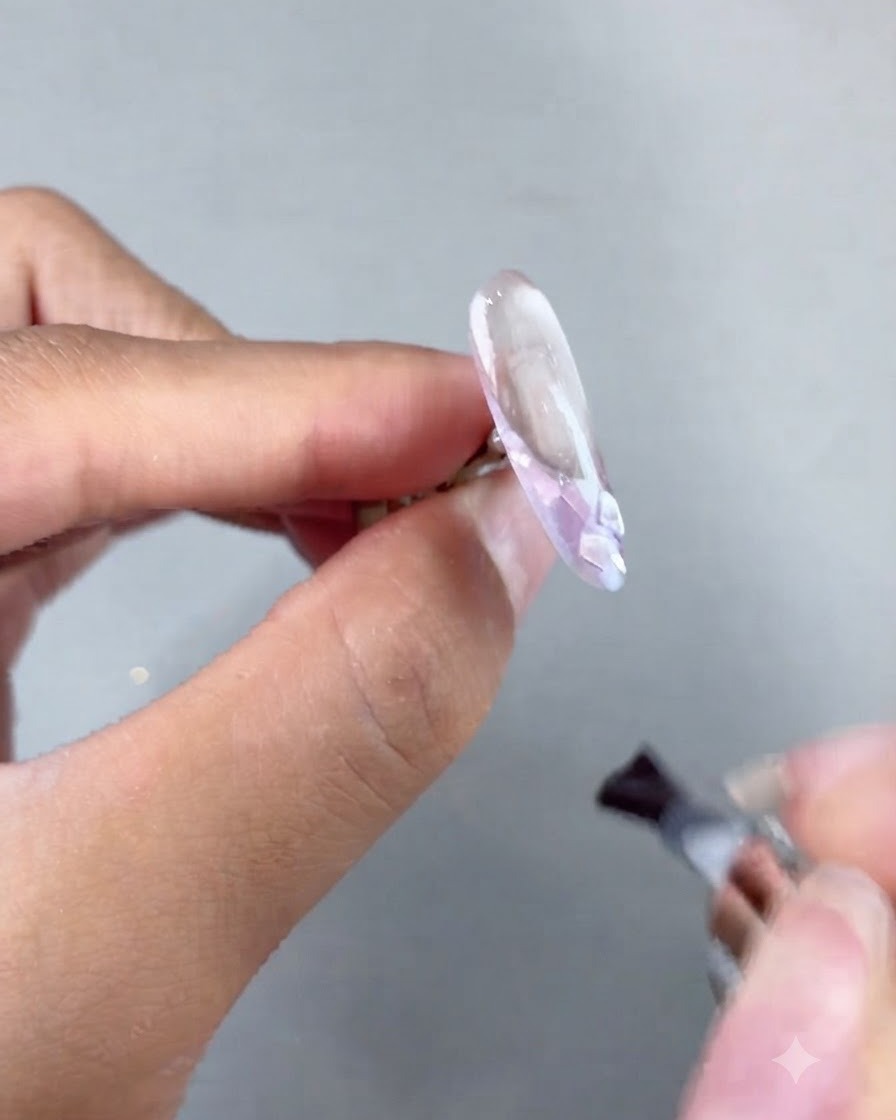 Ein Pinsel trägt Soft Builder Gel über eine verzierte Nagelverlängerung vor dem Aushärten auf.