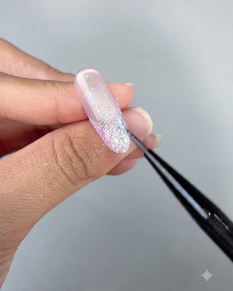 Eine detaillierte Nahaufnahme eines Pinsels verfeinert Cat-Eye-Gel-Details an einem langen, glänzenden Nageldesign.