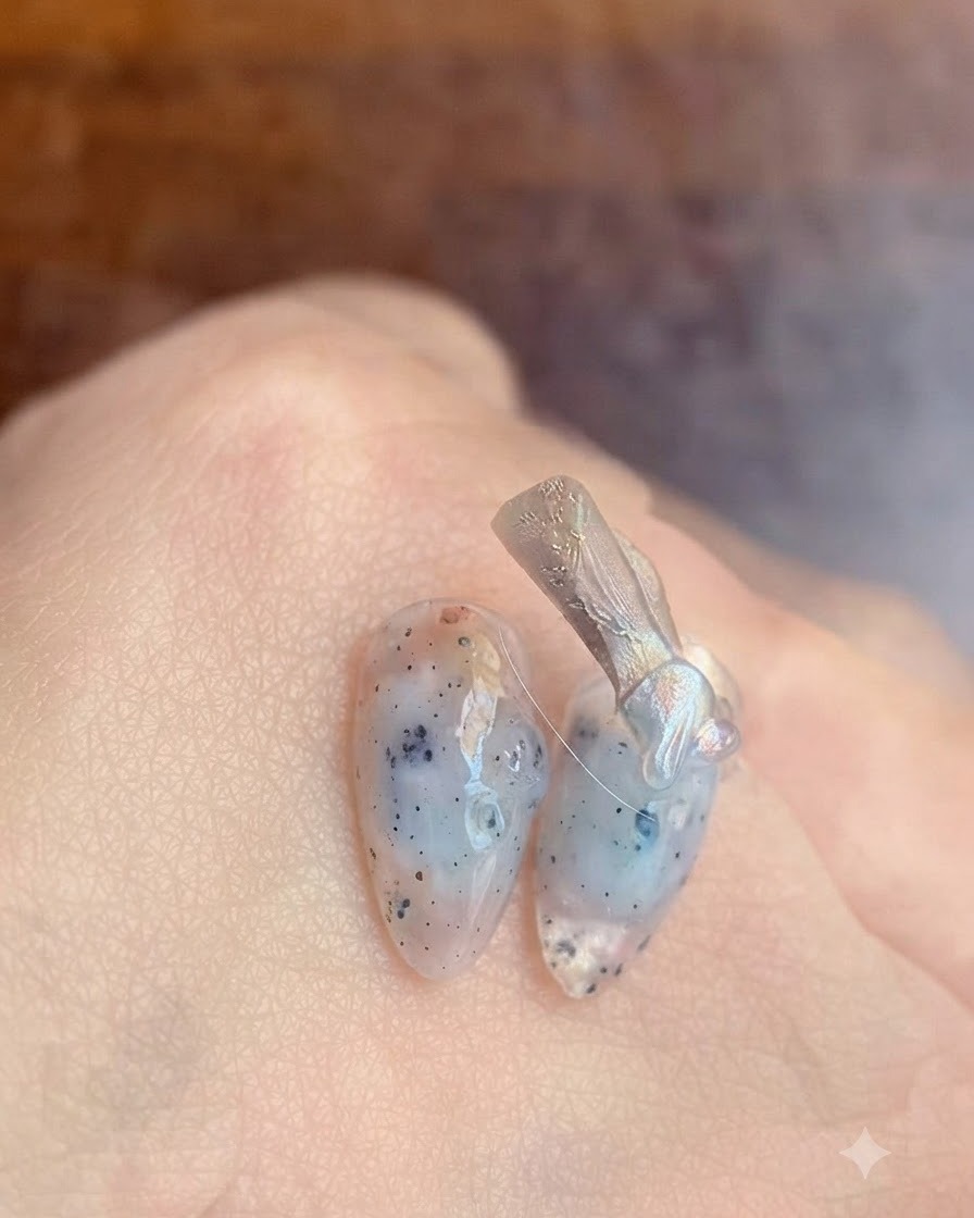 Eine Nahaufnahme eines Nagelpinsels, der einen klaren Base-Coat-Gel auf einen Naturnagel aufträgt.