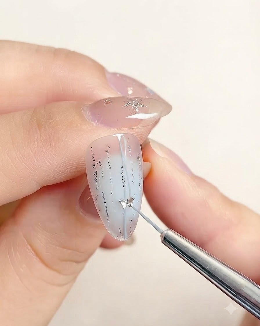 Ein Präzisionswerkzeug platziert einen kleinen sternförmigen Sticker entlang der Mittellinie eines verzierten Nagels.