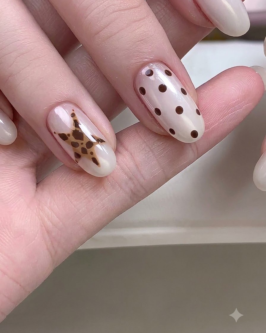 Eine Nahaufnahme einer Hand mit detaillierten Stern- und Polka-Dot-Nagelkunst-Designs.