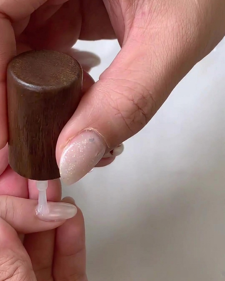 Eine Fräse mit einem flammenförmigen Keramikaufsatz verfeinert sorgfältig den Nagelhautbereich eines Naturnagels.