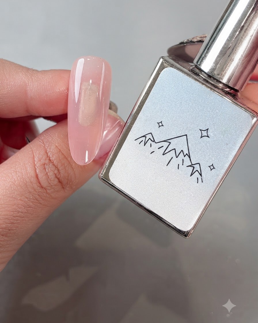 Ein Pinsel trägt White Boiling Water No. 2 Cat-Eye-Gel gleichmäßig auf einen Nagel mit rosa Basis auf.