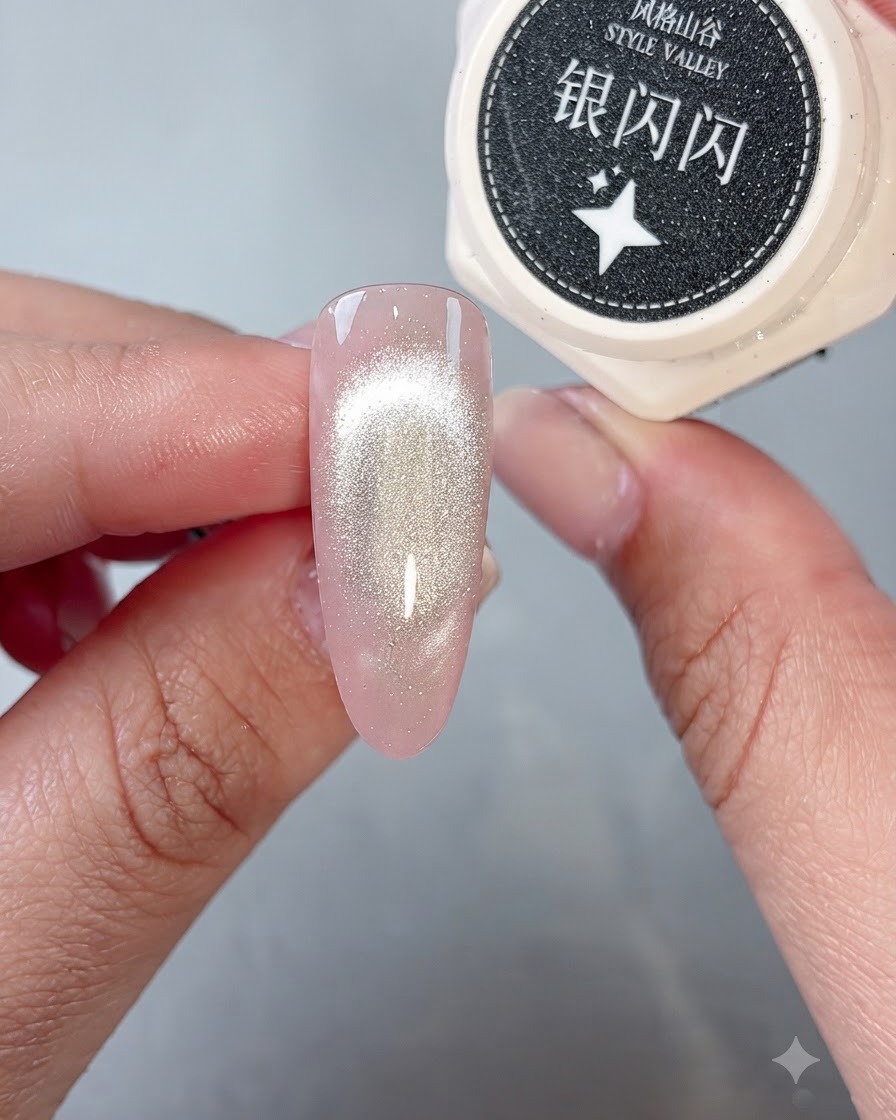 Ein Pinsel platziert funkelndes Silberglitter-Gel auf der Spitze eines fertigen Cat-Eye-Nagels.