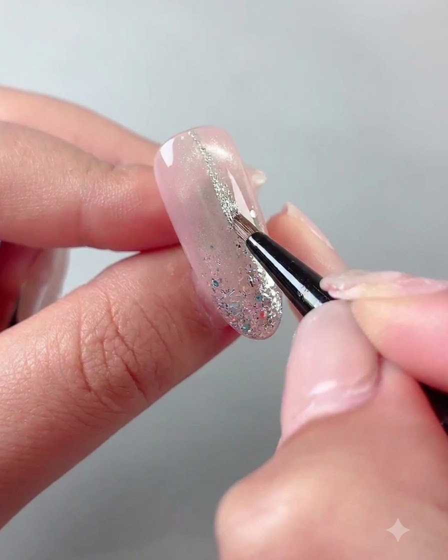 Ein feiner Liner-Pinsel zeichnet dünne Silberglitter-Linien auf eine ausgehärtete Nageloberfläche.