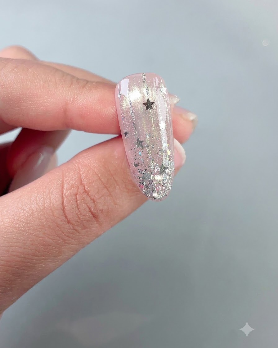 Ein fertiges, glänzendes, sternenbesetztes Nageldesign vor einem neutralen Hintergrund.