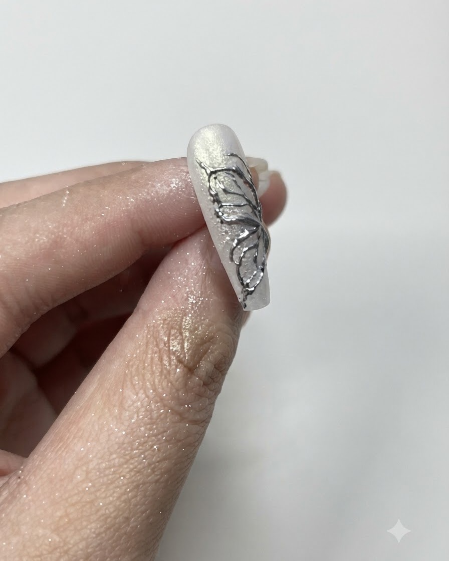 Ein flauschiger Pinsel entfernt überschüssiges Silver-Chrome-Puder von den Rändern eines manicierten Nagels.