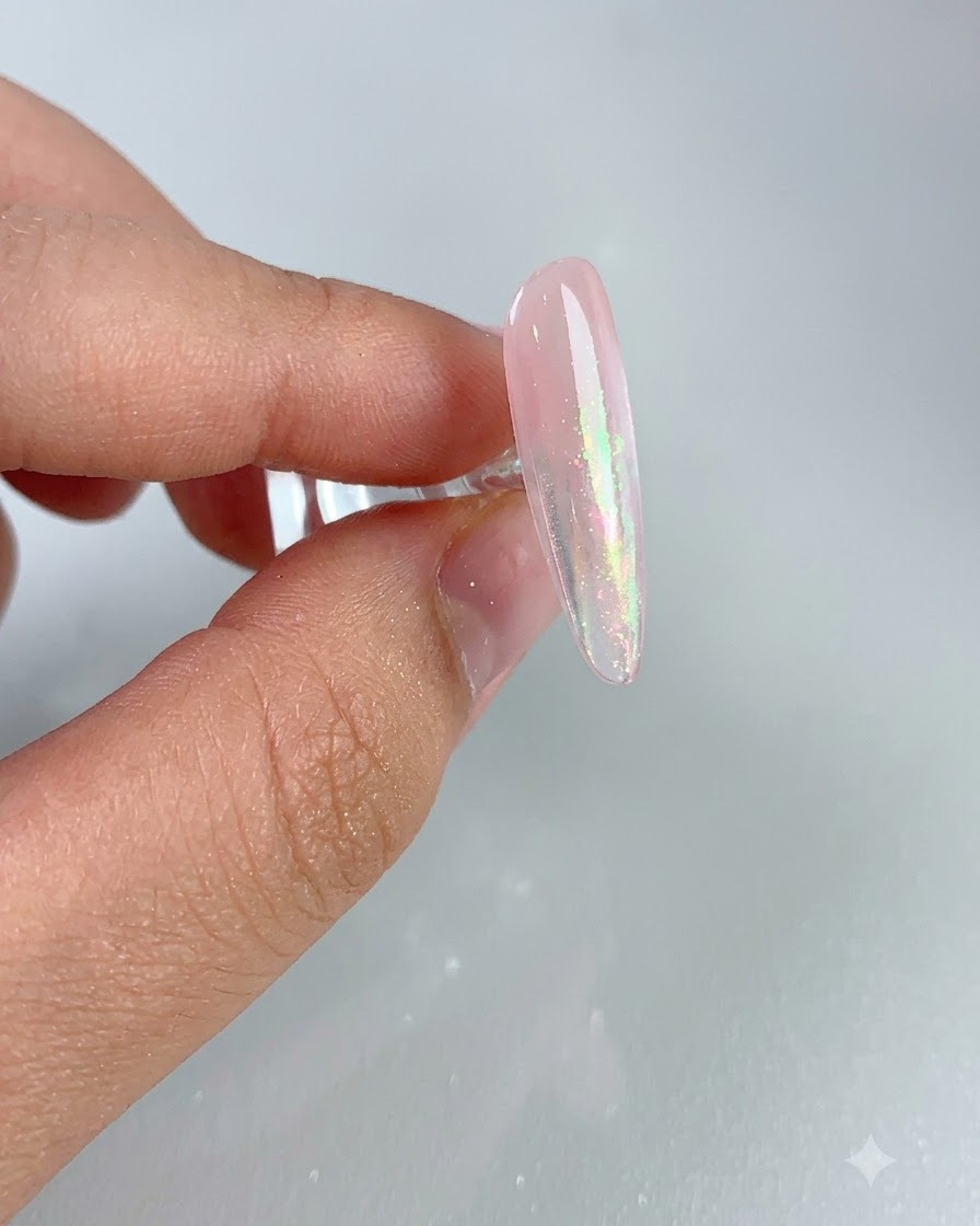 Eine Nahaufnahme eines glänzenden rosa Nagels, der nach dem Abkehren des überschüssigen Puders einen schimmerten Aurora-Effekt zeigt.