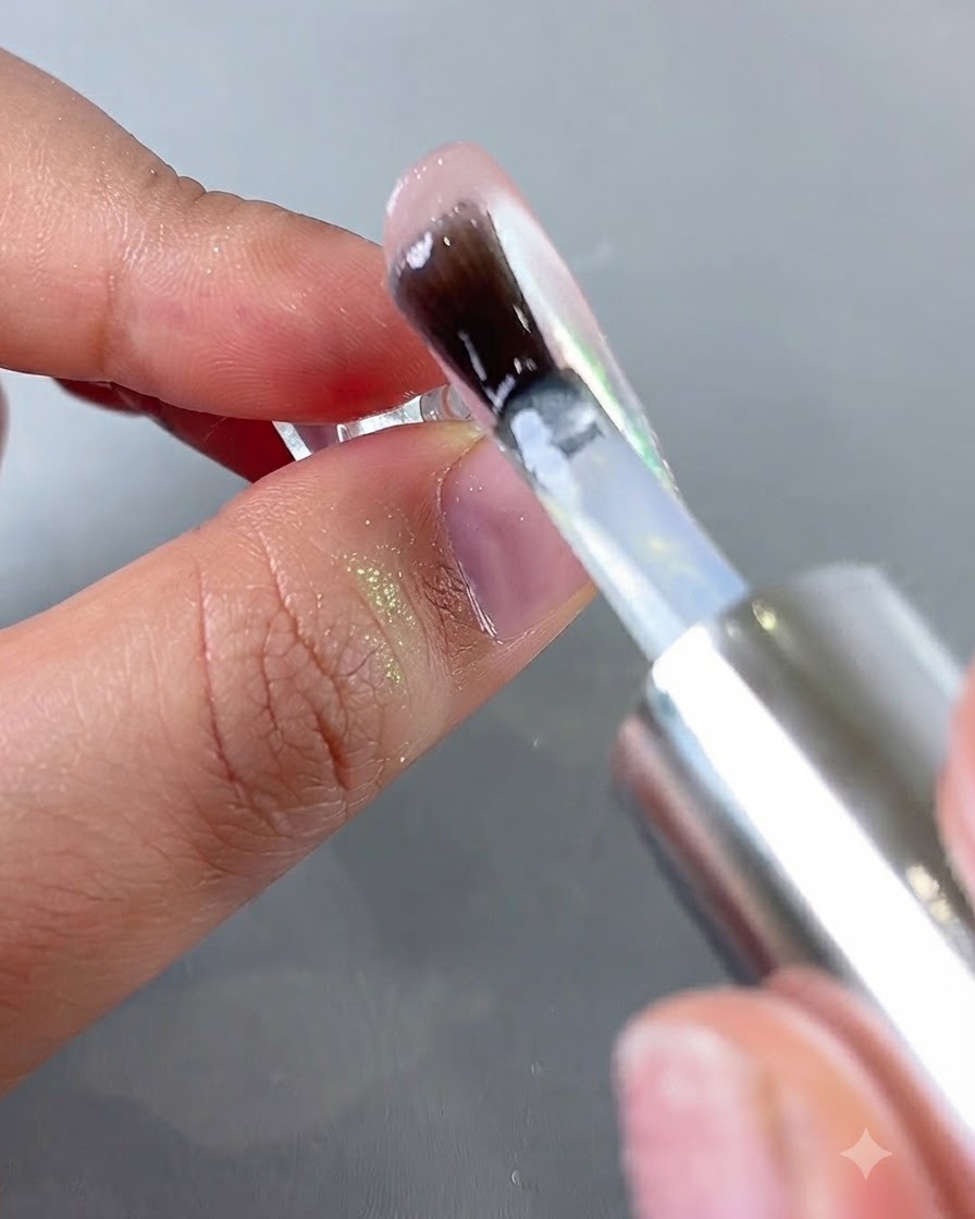 Ein Pinsel trägt einen klaren Top-Coat über eine schimmernde Aurora-Chrom-Nageloberfläche auf.