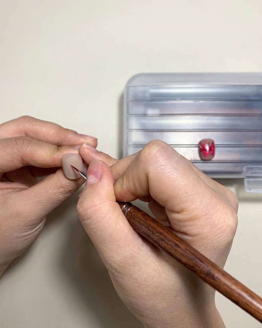 Eine Hand platziert ein fertiges Gel-Nageldesign unter einer UV- oder LED-Aushärtungslampe.