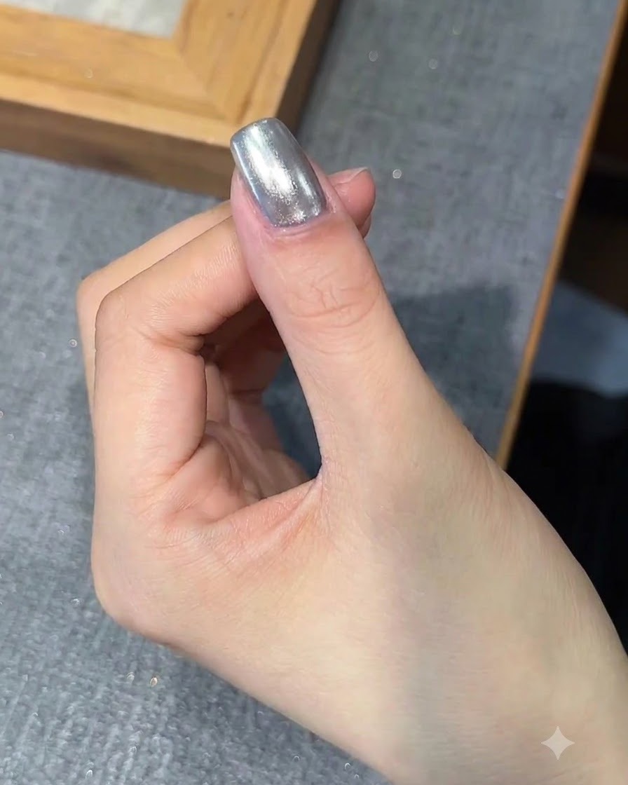 Ein Pinsel trägt eine Schicht Base-Gel über den mit Chrom veredelten Nagel auf.