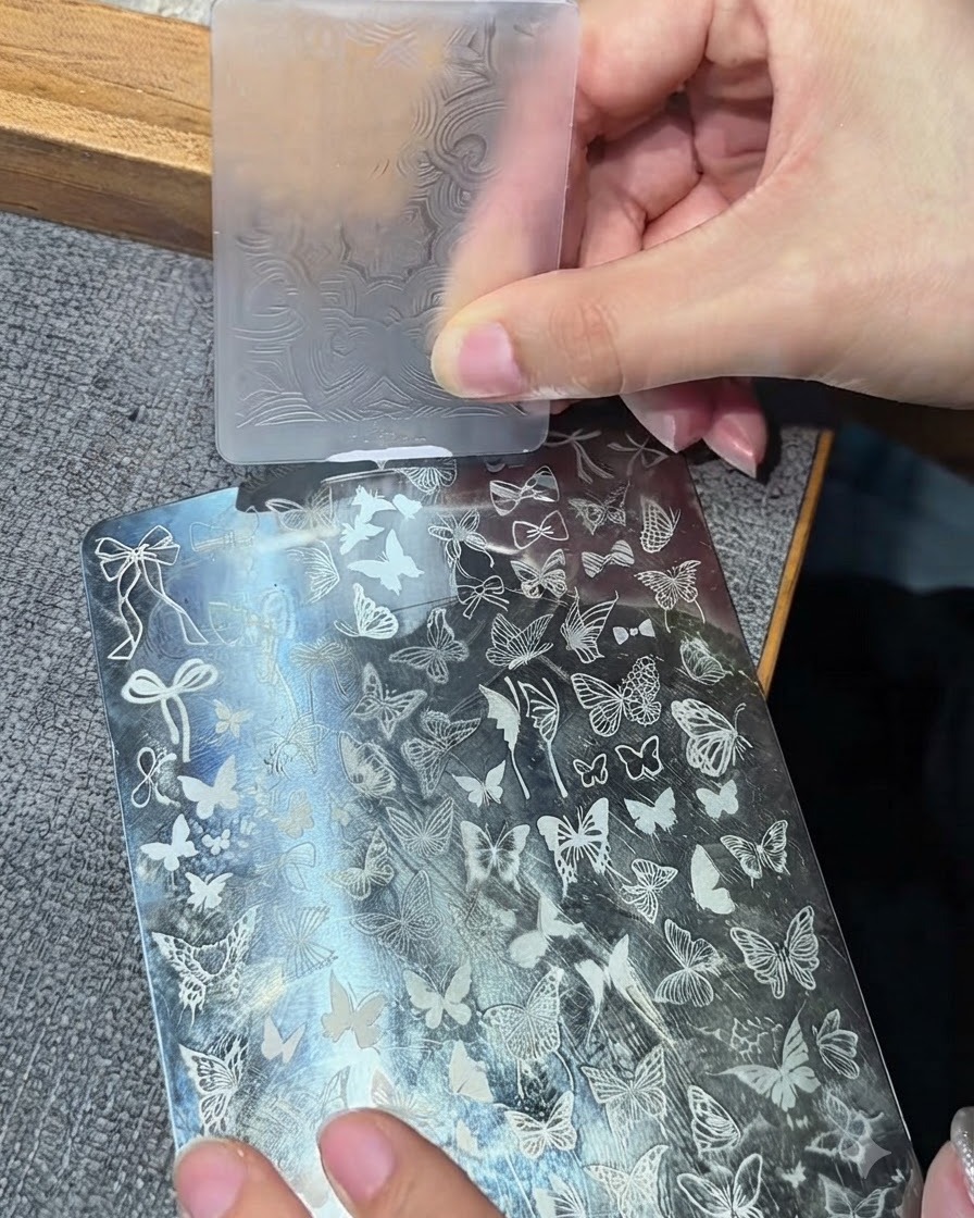 Ein klarer Silikon-Stamper-Kopf drückt auf eine Metall-Stamping-Platte, um ein weißes Design aufzunehmen.