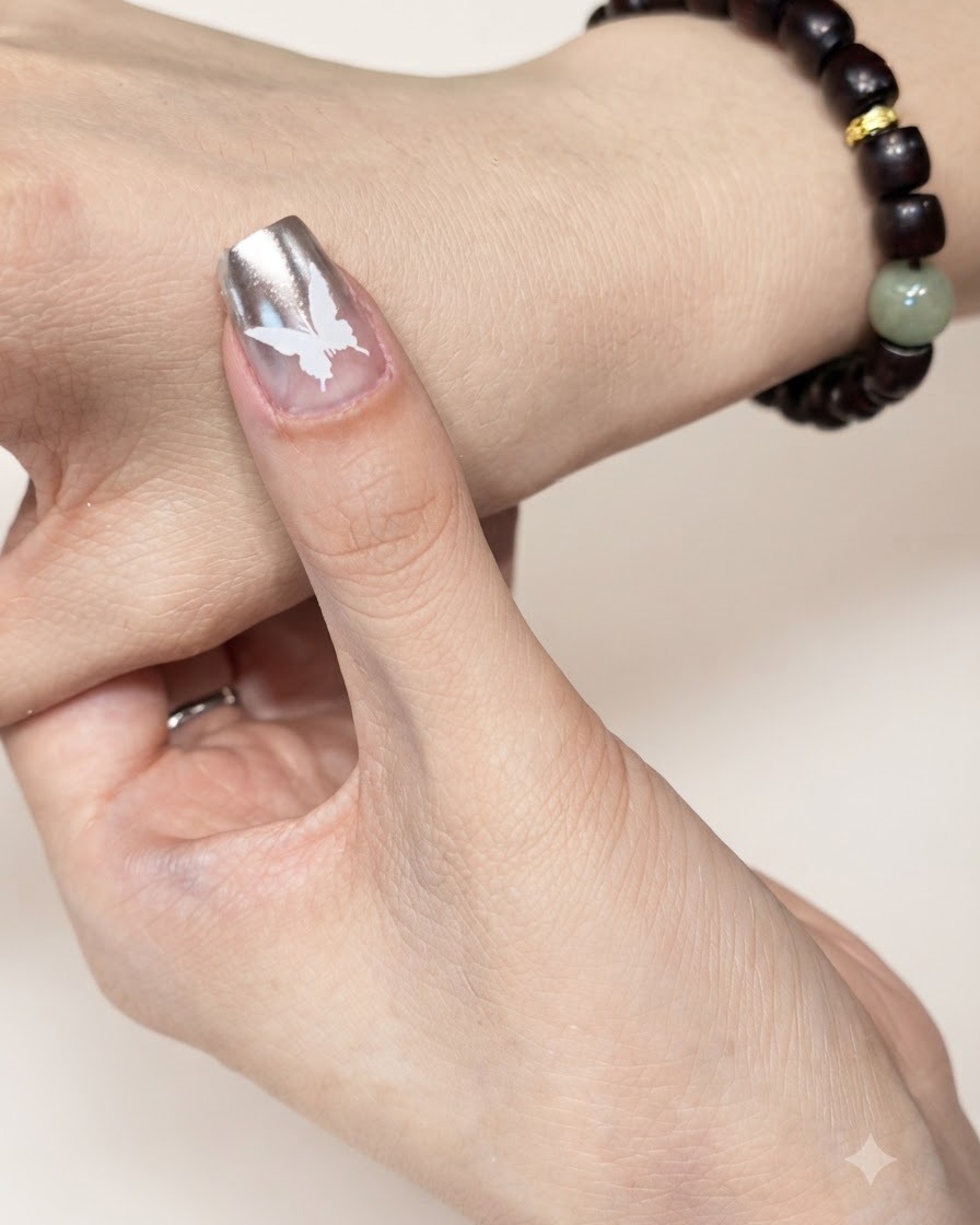 Ein manikürter Fingernagel mit einem weißen Schmetterlingsdesign wird unter einer UV- oder LED-Härtungslampe positioniert.