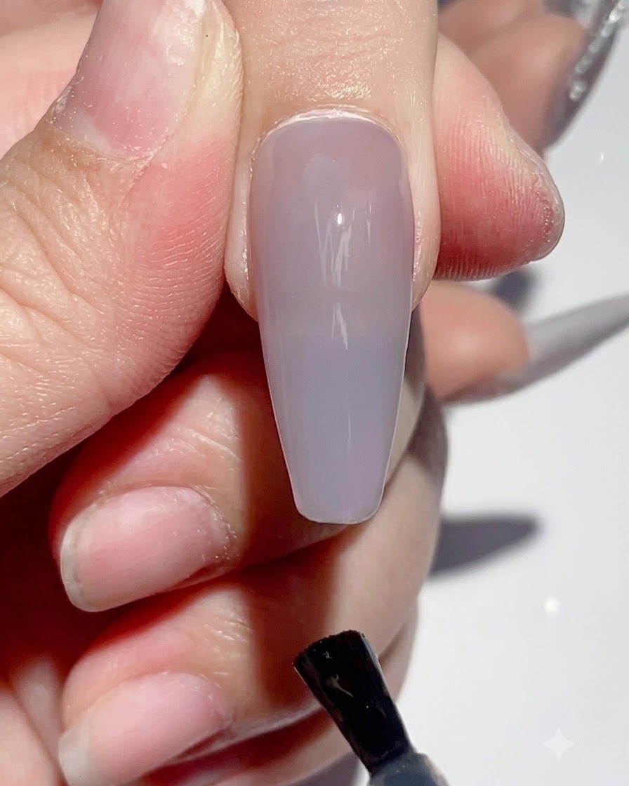 Eine Hand wird während des Aushärtens unter eine UV-LED-Nagellampe gelegt.