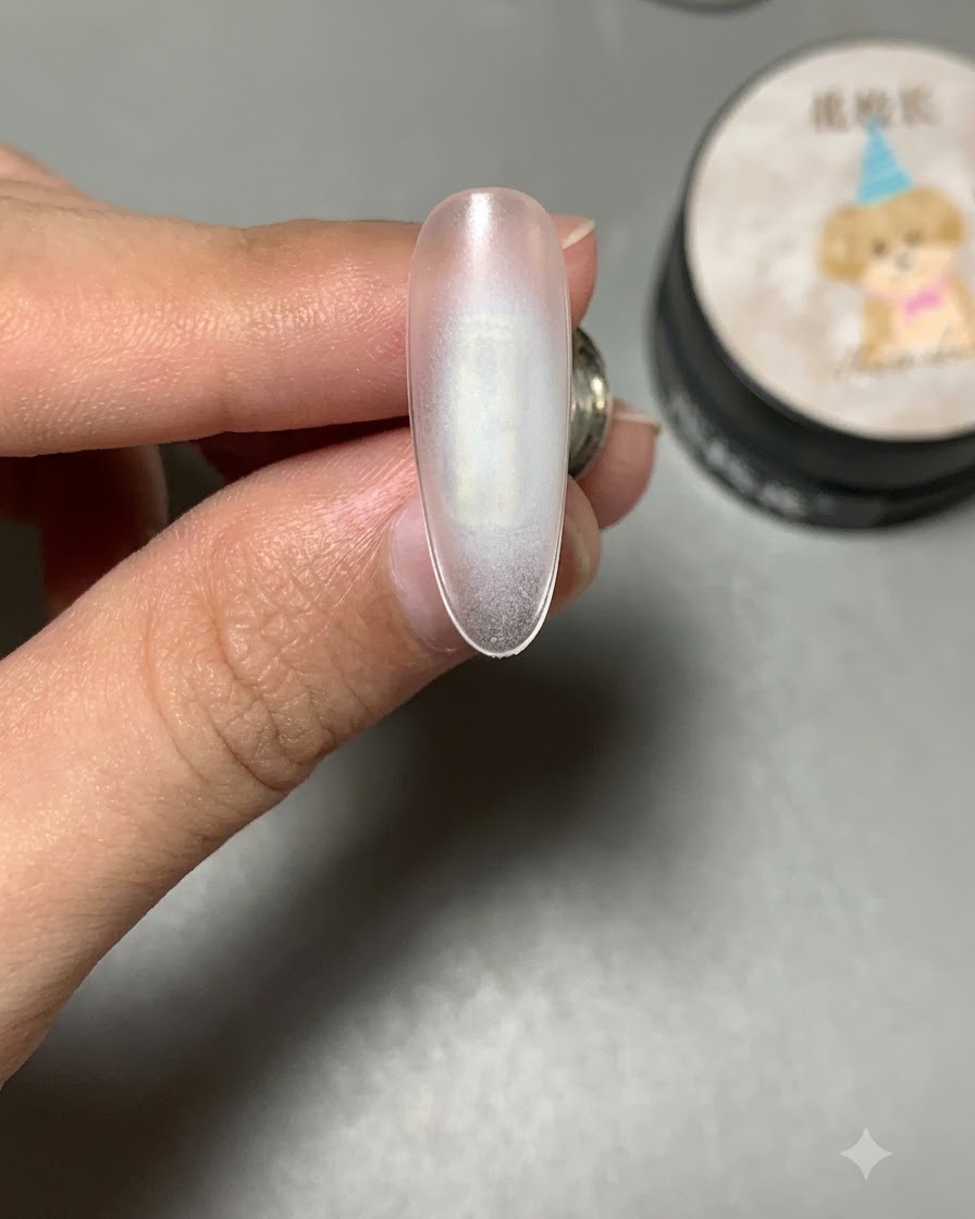 Ein Nagel, der mit klarem Verstärkungsgel beschichtet ist und vor einem Produktglas gehalten wird.