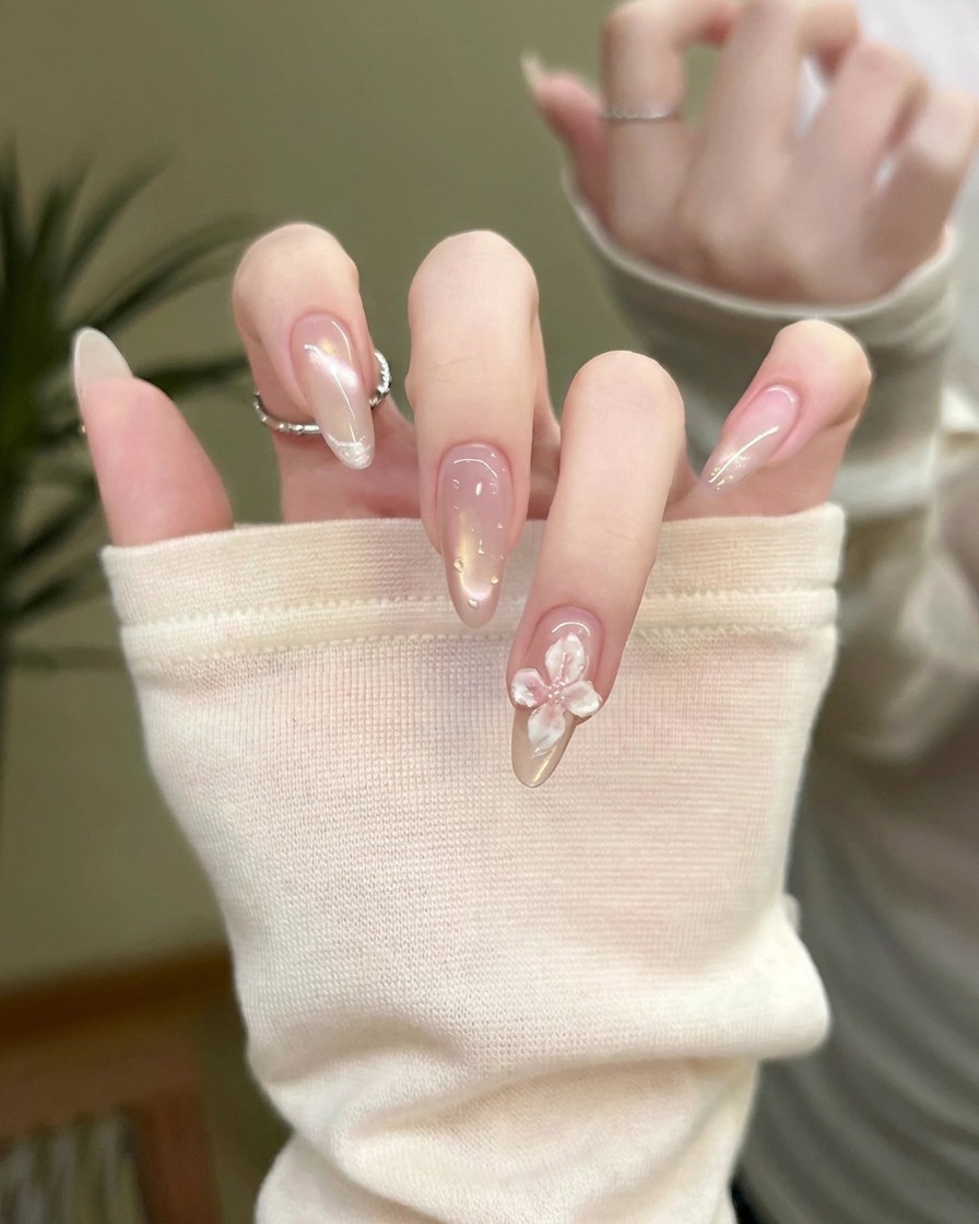 Ein feiner Detailpinsel trägt kleine erhöhte Top-Coat-Tropfen, die Wassertropfen ähneln, auf einen fertigen Nagel auf.