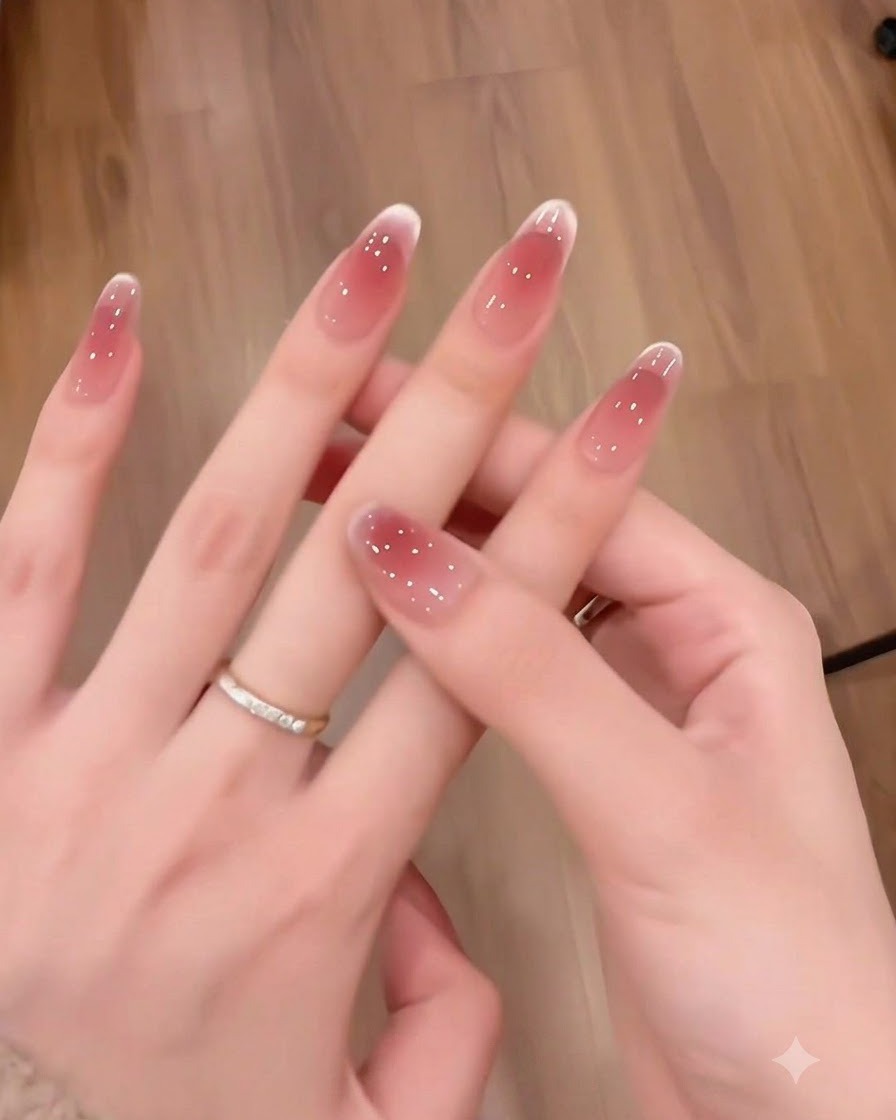 Nahaufnahme von langen, mandelförmigen Nägeln mit einem glatten Rot-zu-Rosa-Farbverlauf.