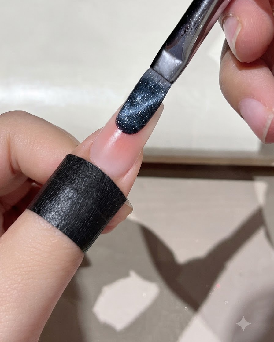 Ein Pinsel trägt dunkelblaues Cat-Eye-Gel auf die Kante eines vorbereiteten Nagels auf.