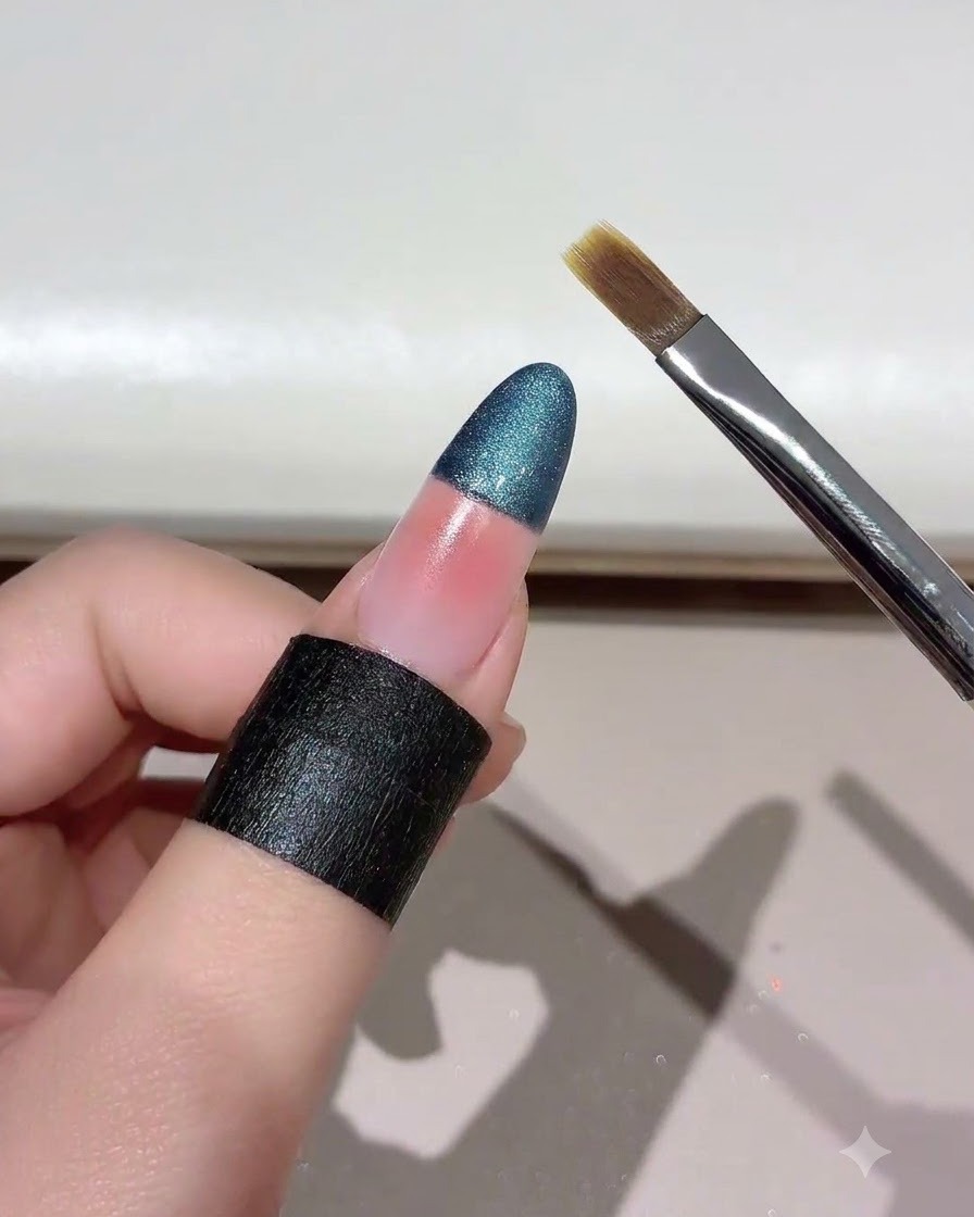 Ein Nagelpinsel wird in einem Winkel nahe einem farbverblendeten Cat-Eye-Nagel gehalten.