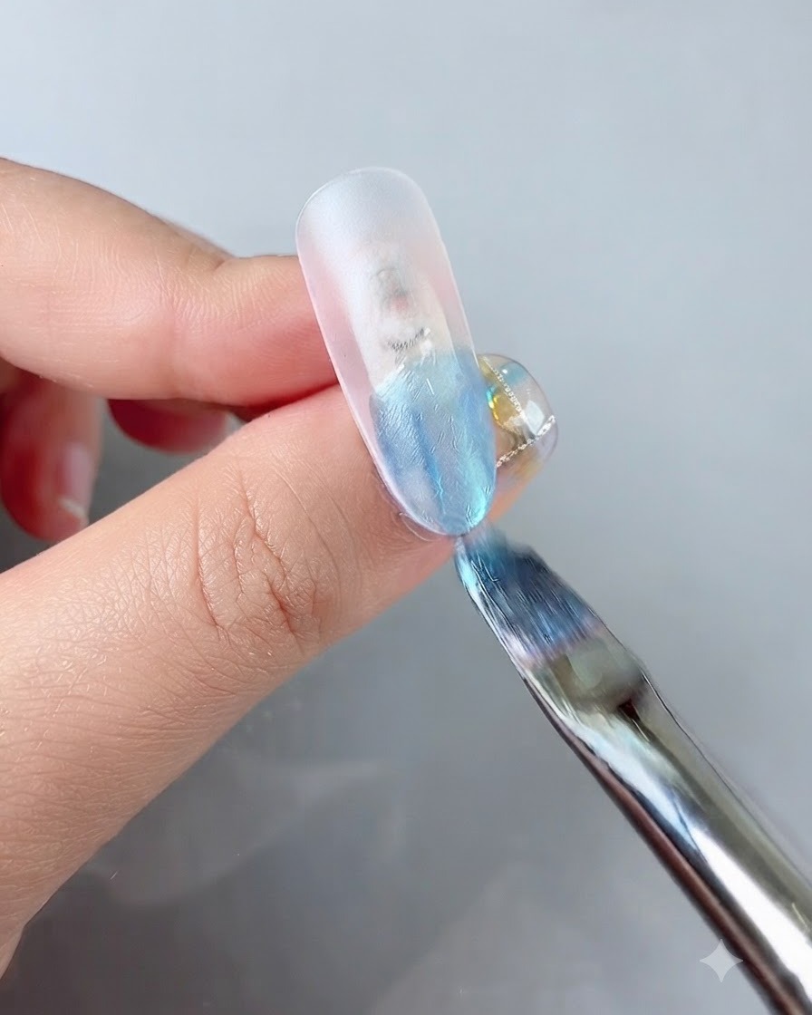 Ein Nagelpinsel trägt ein leuchtendes blaues Farbgel auf die Spitze einer Tip-Modellage auf.