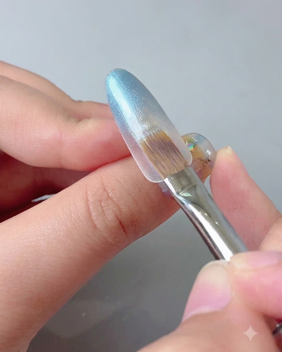 Ein Magnetwerkzeug wird nahe an eine blaue Nagelspitze gehalten, um den Cat-Eye-Glitzer zu bündeln.