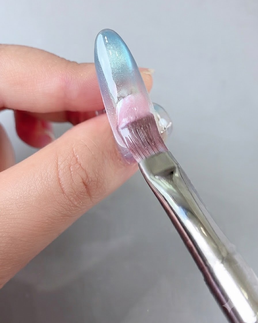 Ein Pinsel trägt rosa Gel auf den hinteren Nagelbereich auf.