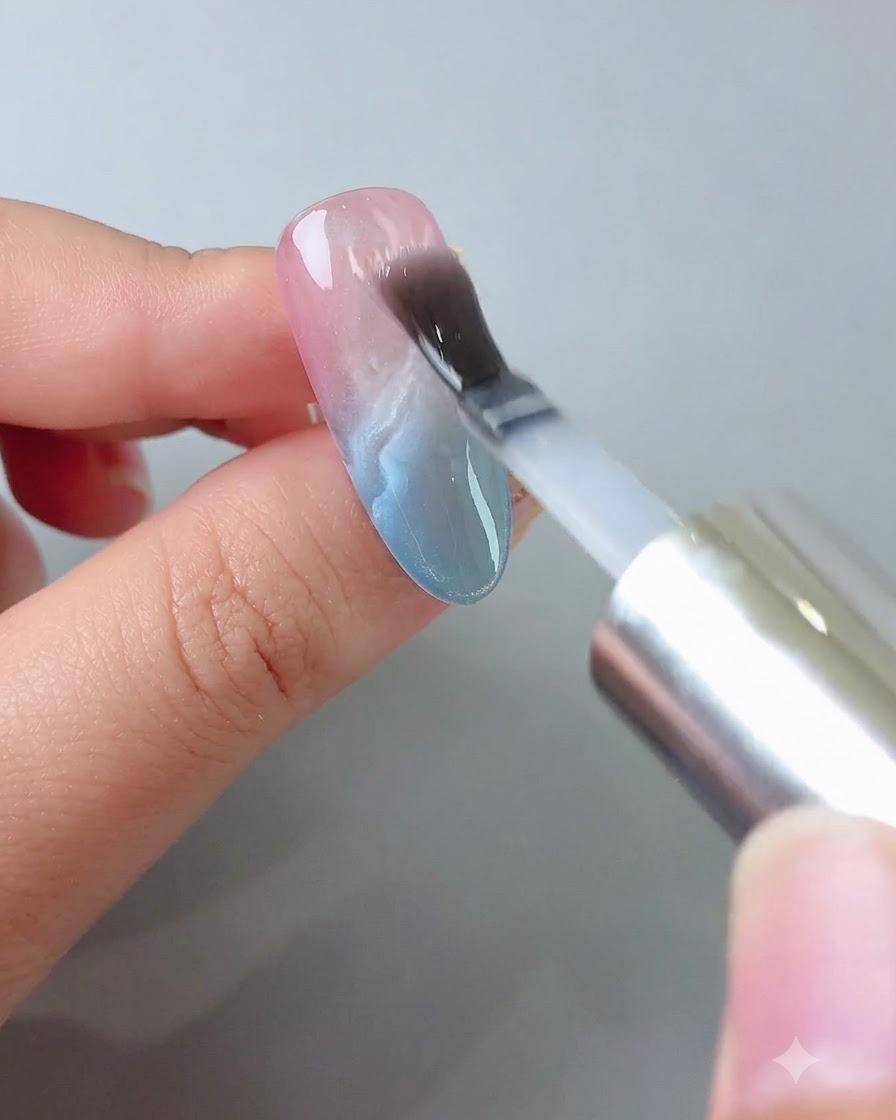 Ein Pinsel trägt eine klare Schicht Builder Gel glatt über den verzierten Nagel auf.