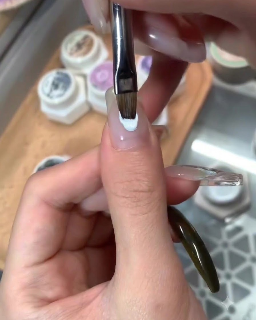 Ein Pinsel trägt einen glänzenden Überzugslack über fertige Nagelkunst im blauen Design auf.
