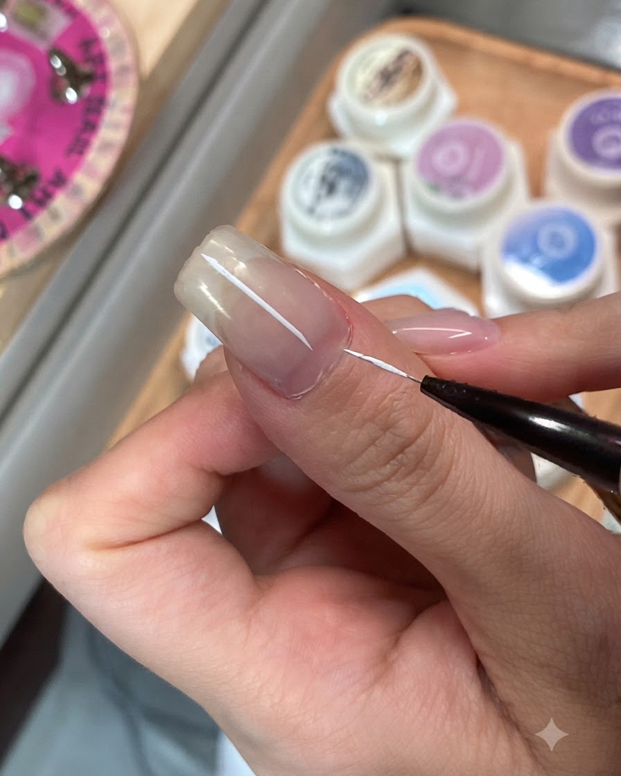 Ein feiner Detailpinsel trägt Überzugslack auf einen einzelnen Fingernagel auf.